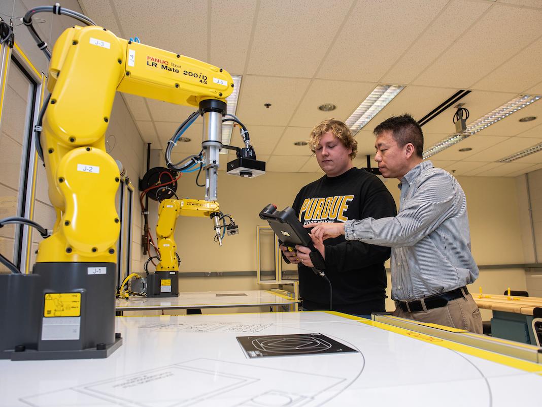 Student works in an engineering lab with a robotic arm.