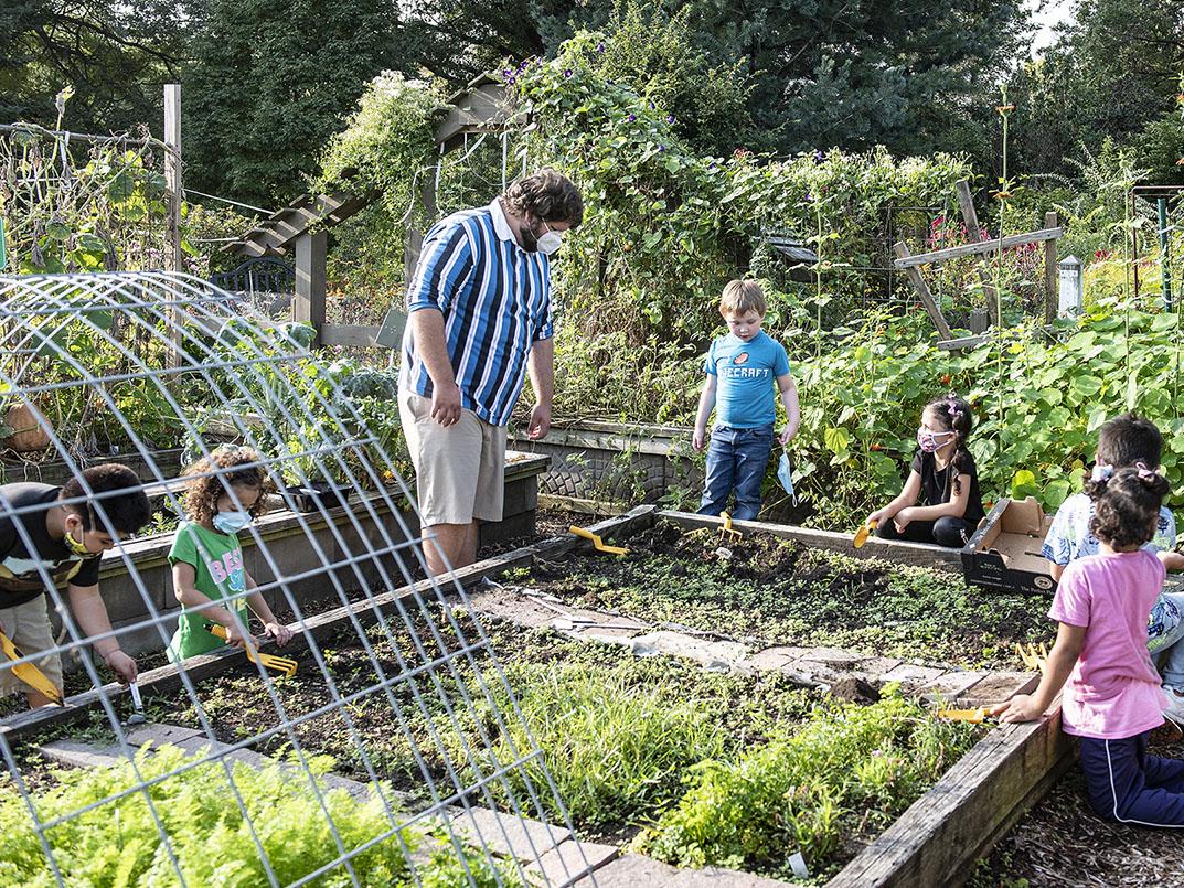 An adult and several children are working in the School of Education's urban garden.