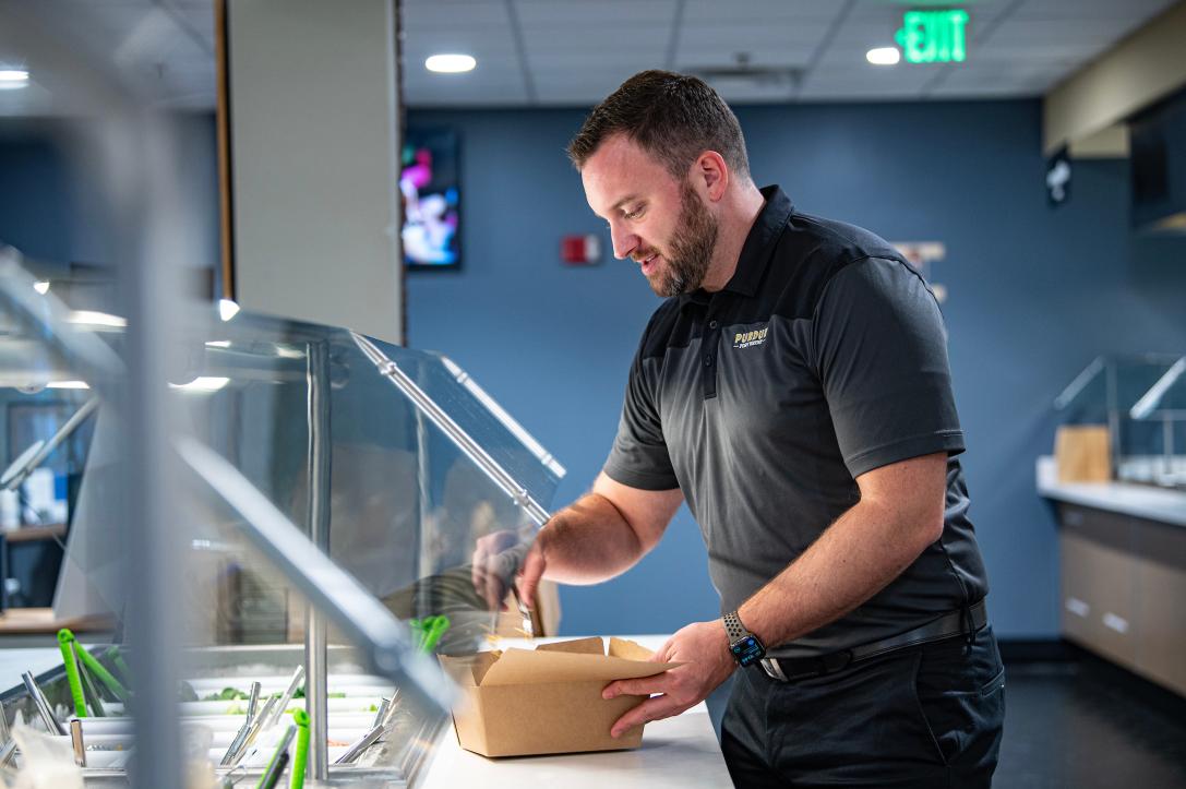 PFW employee fills a take-out box of food for lunch.