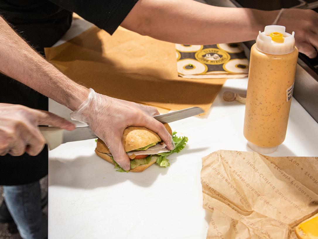 A dining services employee makes a sandwich.