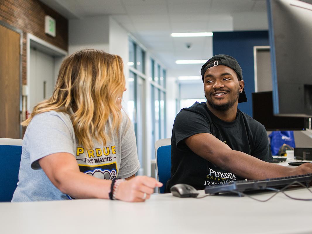 Students working together at a computer in the library.