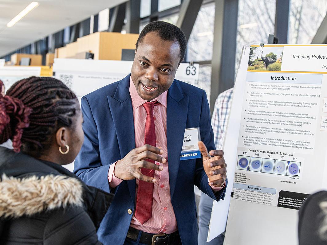 A student explains his research project to a judge at the symposium