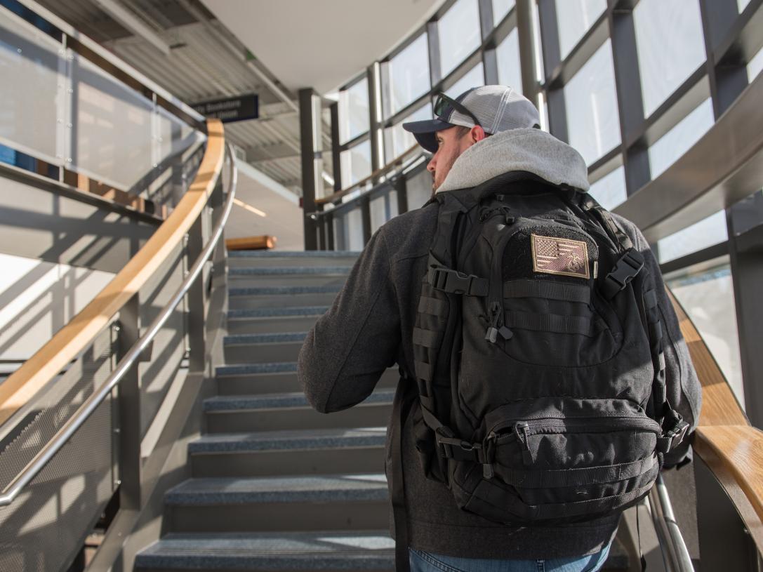 Veteran student walking up a staircase on campus.
