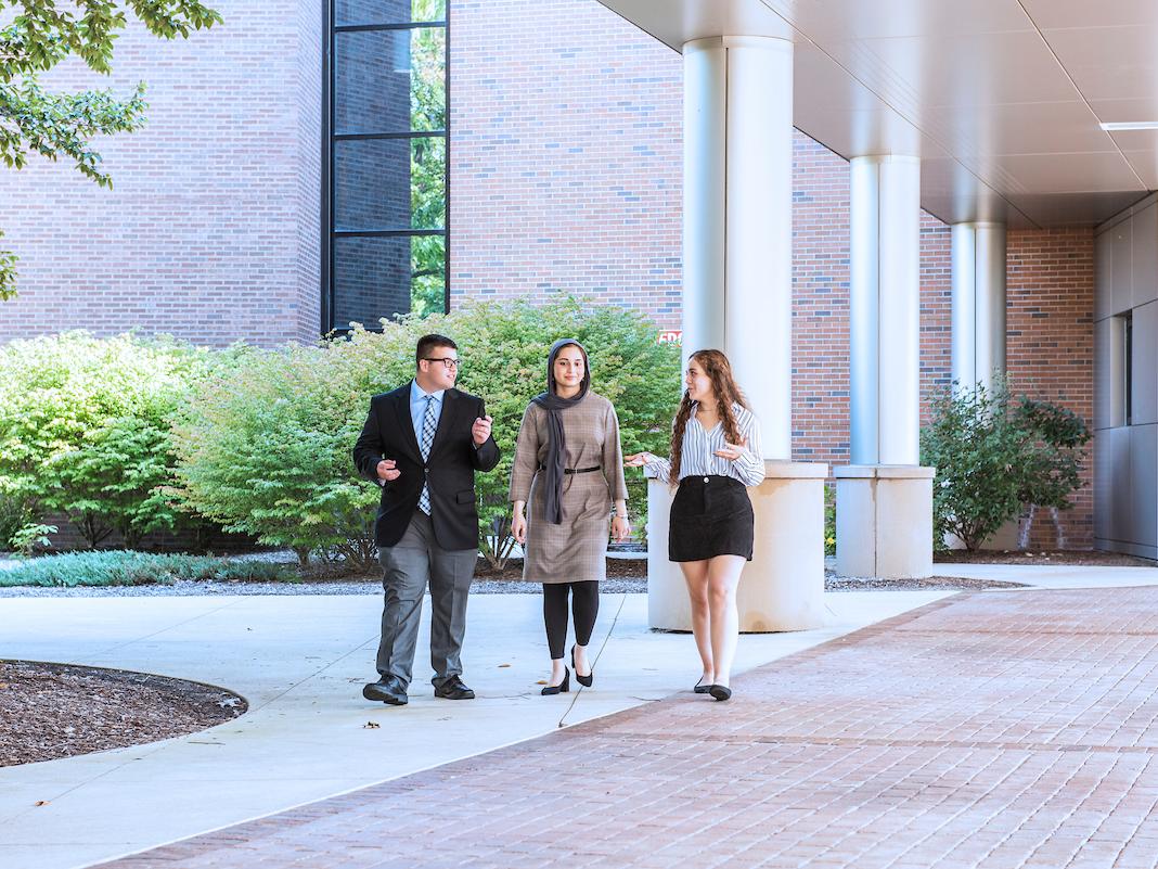 Students in business attire walking outside on campus.
