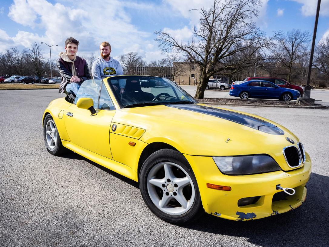 Two engineering students are siting in a restored BMW