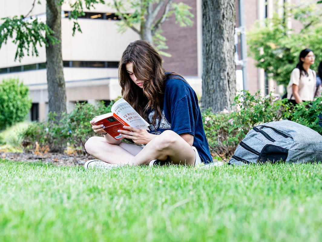 Student reading a book outside.