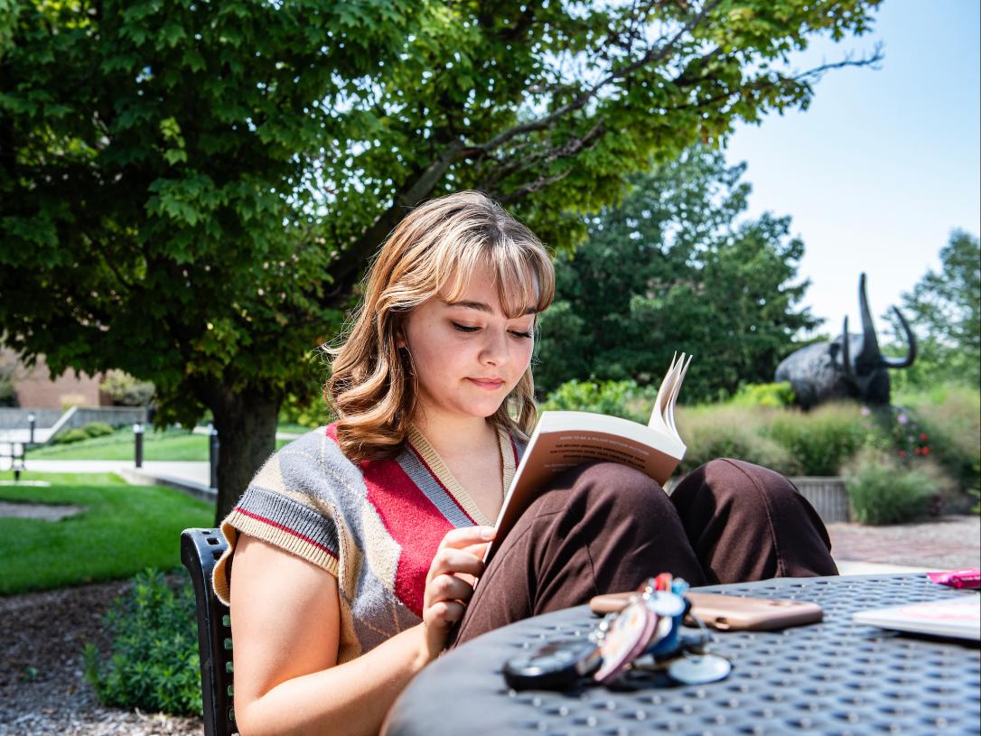 Student reading a book outside.