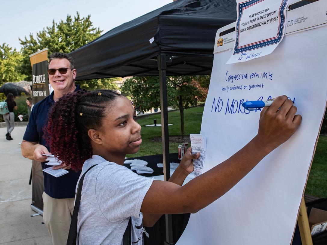 Student writes on a poster about Constitution Day.