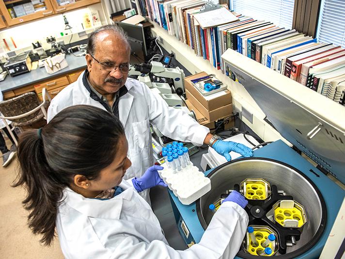Ahmed Mustafa working with a student in a biology lab.