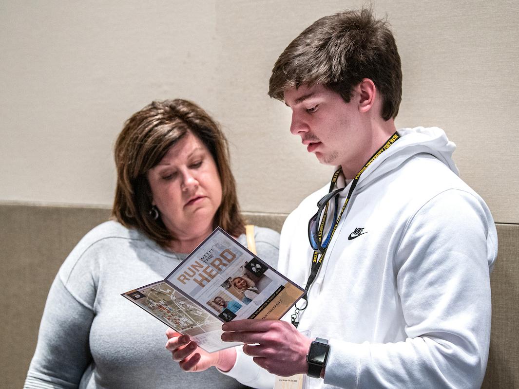 A prospective student and parent review the itinerary for Spring Campus Visit Day.