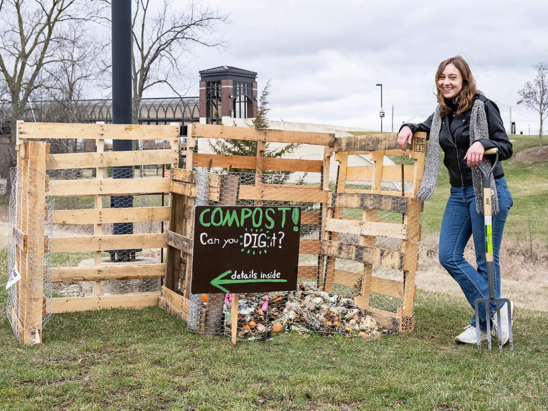 Emma Coville is standing next to compost bin