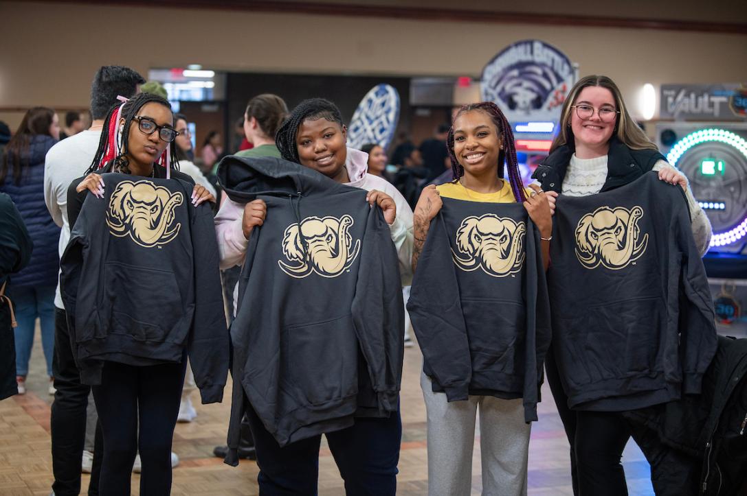 Students hold up Mastodon-printed sweatshirts.