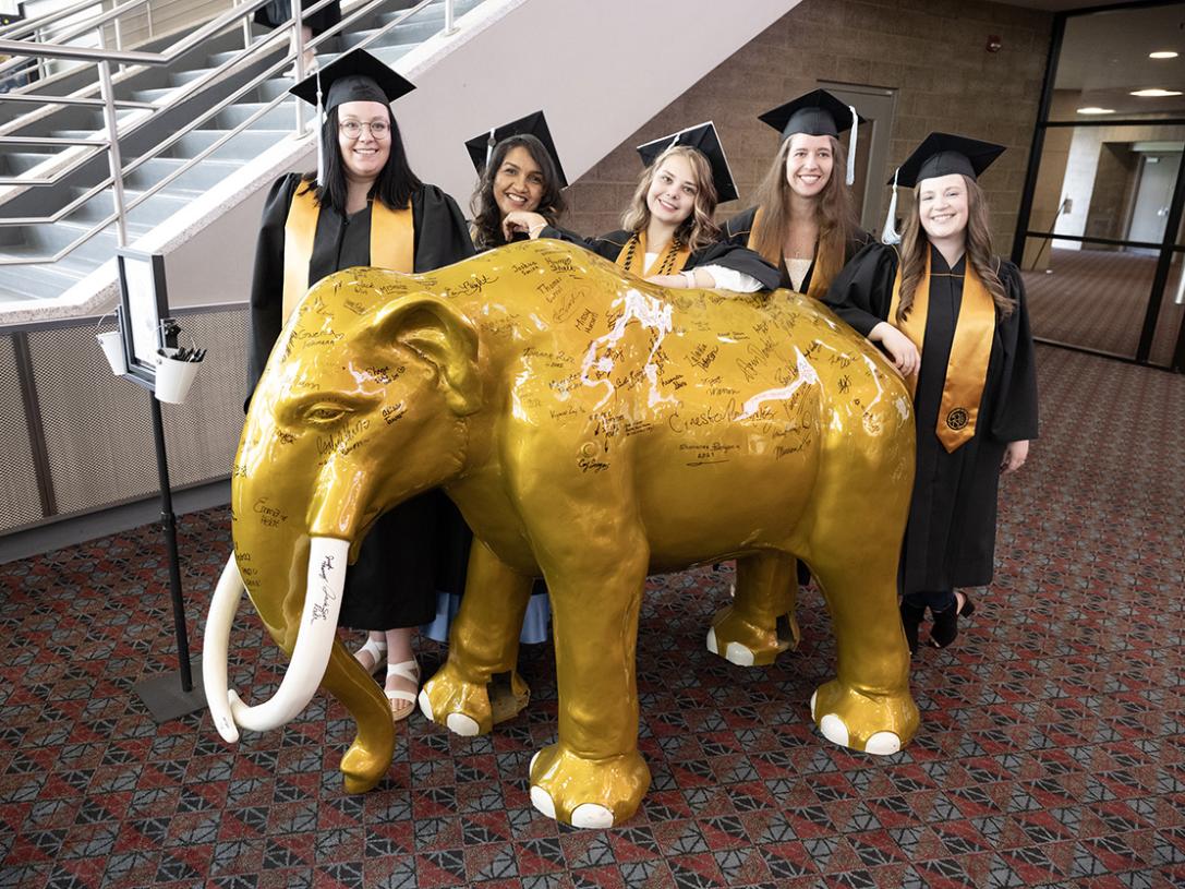 Graduates with a mastodon statue