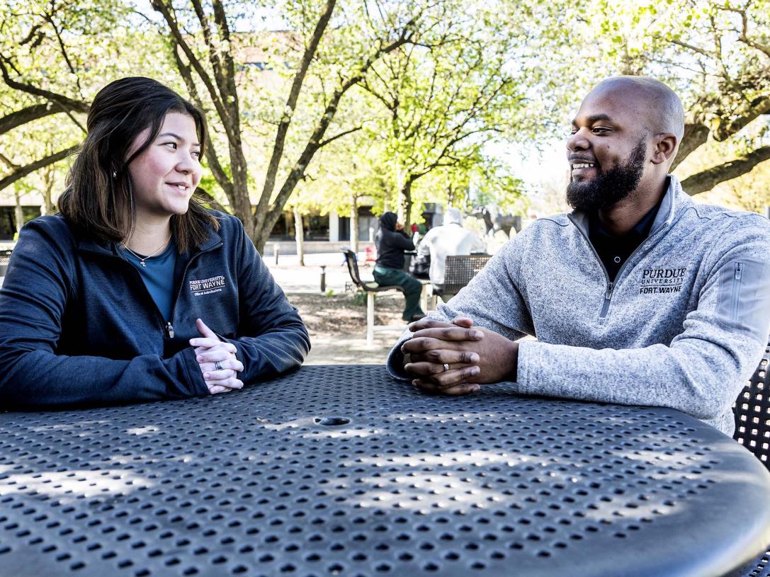 Madeline Minobe and DeShawn Woods are sitting at a table