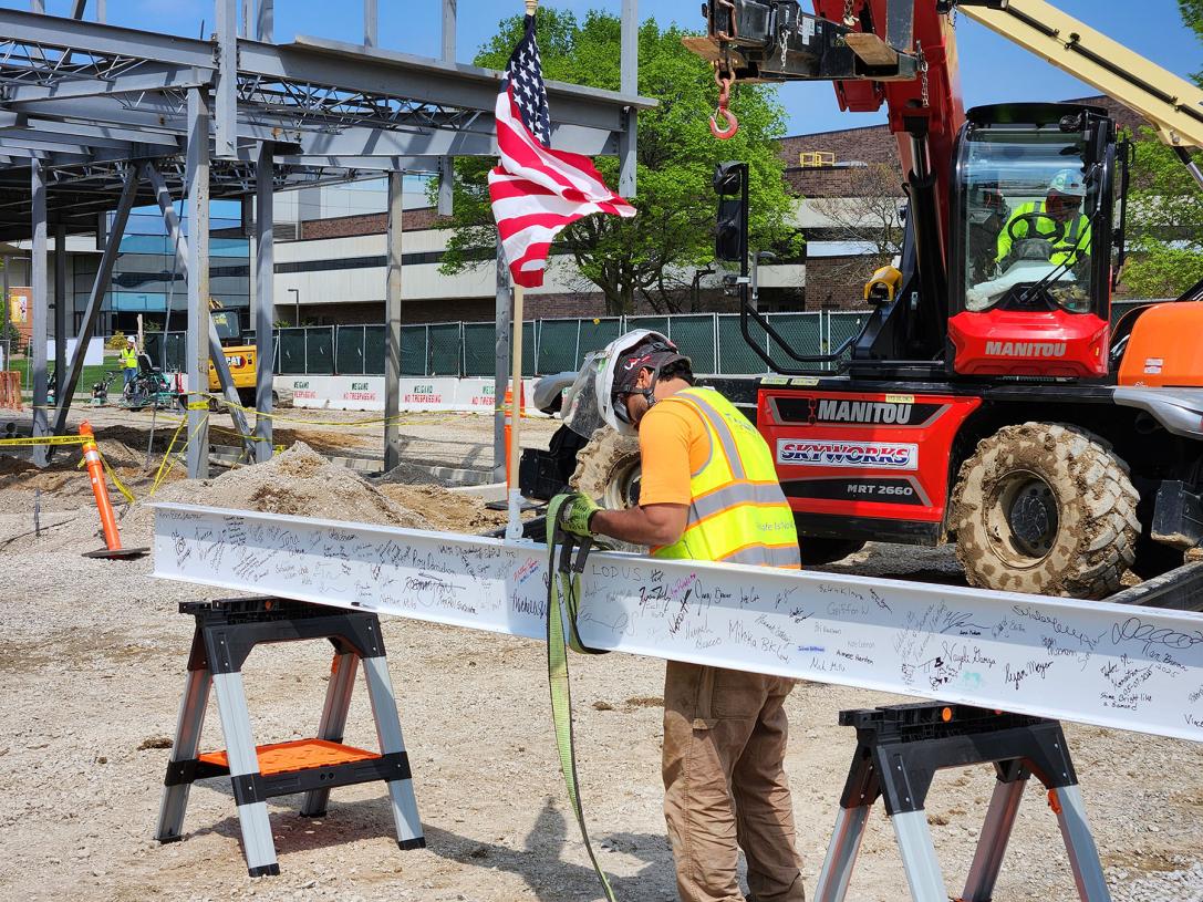 A construction worker readies the autographed beam before it is hoisted to the top of the building.