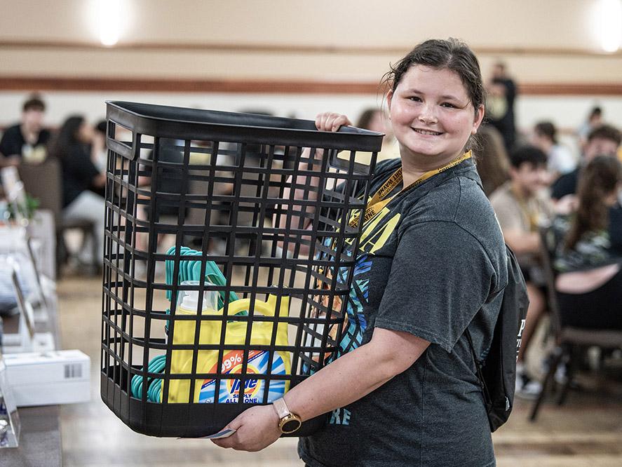 A new student is holding a laundry basket at NSO bingo night