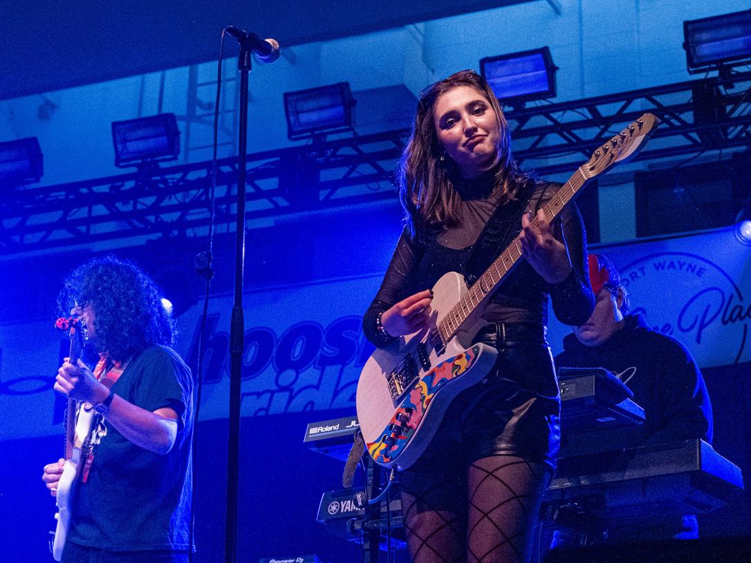 Hailee Richmond is playing guitar while performing with a band