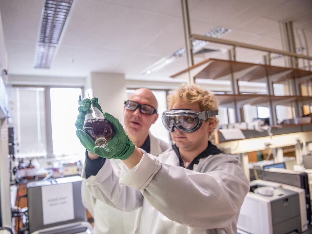 Chemistry student wearing protective goggles and gloves during an experiment.