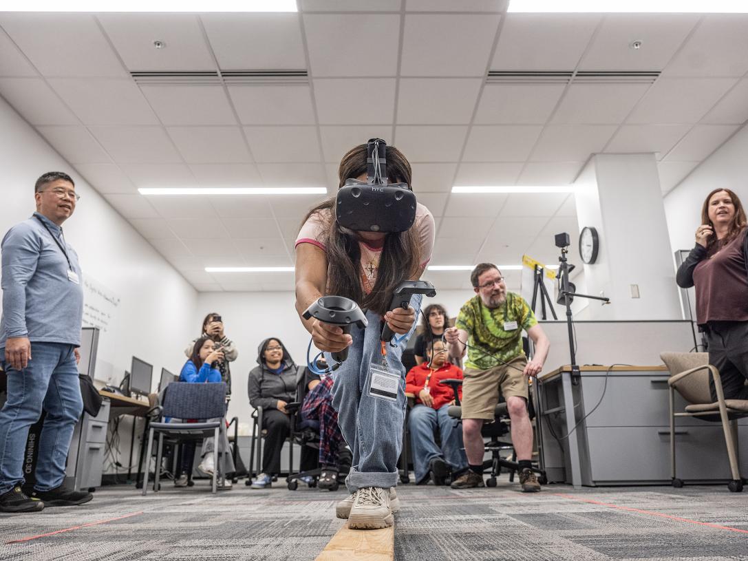 A student is walking on a balance beam while wearing a VR headset