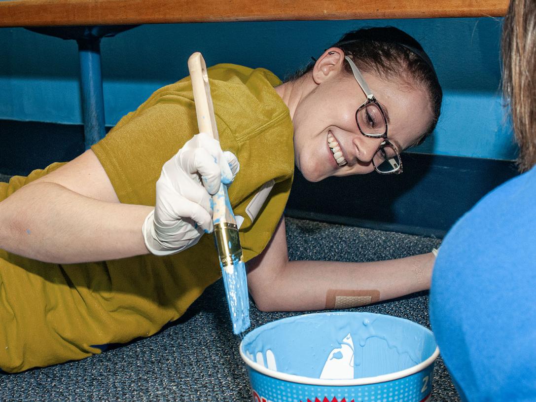 A student is painting while taking part in community service.