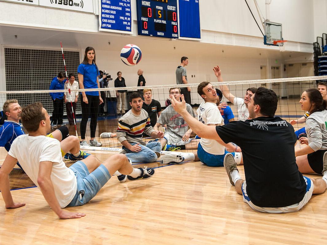 Two teams are playing volleyball while sitting down