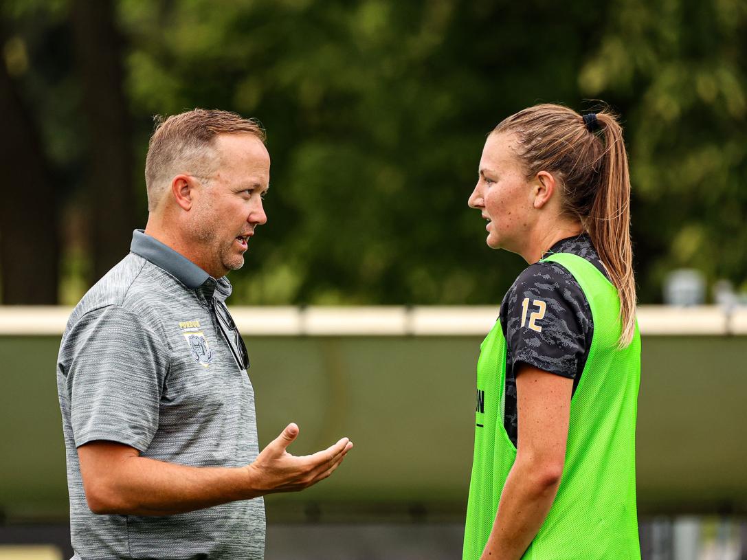 A coach is conferring with a soccer player