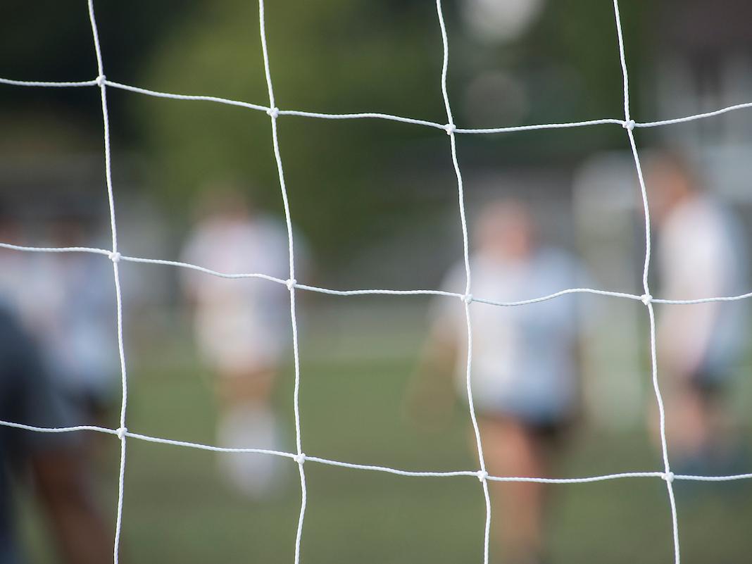 Soccer players seen through a goal net