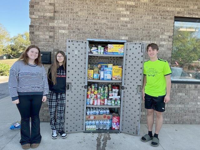 Sociology students standing next to an outdoor food pantry