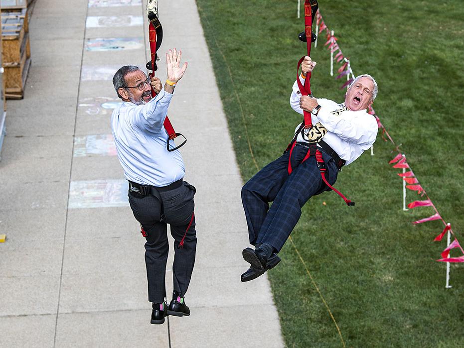 Deans Ron Friedman and John O'Connell are traveling down a zipline