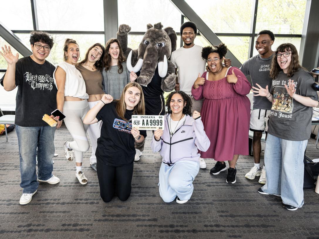 A group of students pose with Don to show off a PFW license plate