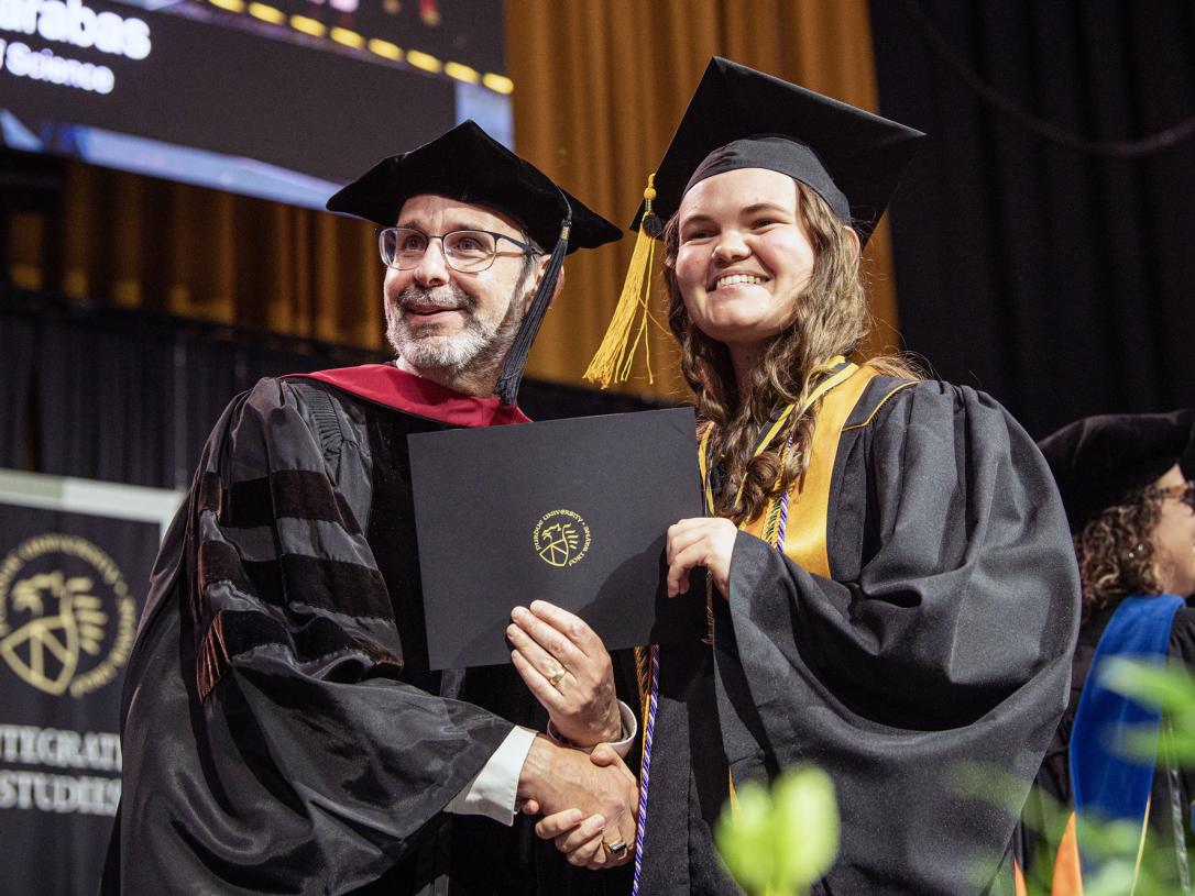 A student and dean shake hands during the 2026 commencement ceremony