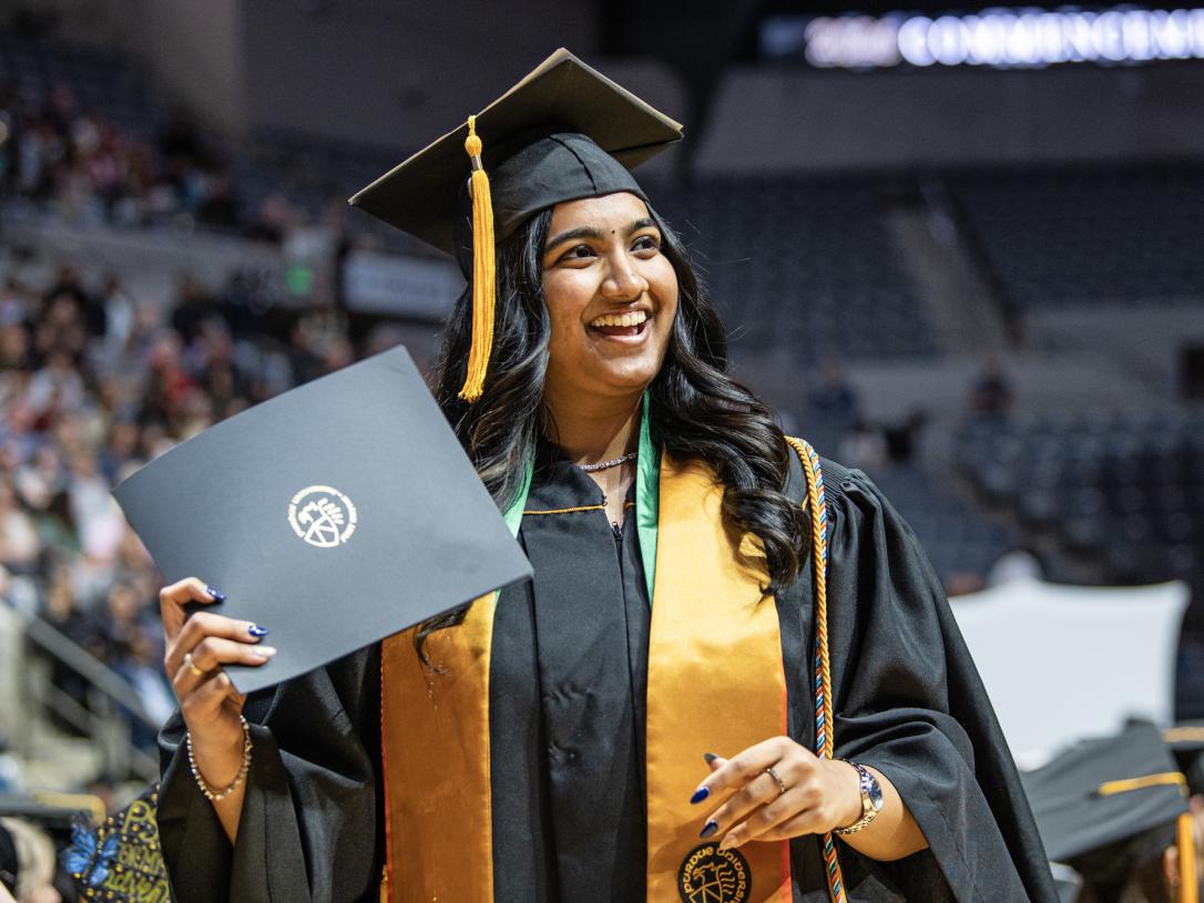 Female student poses with a degree at the 2026 commencement ceremony