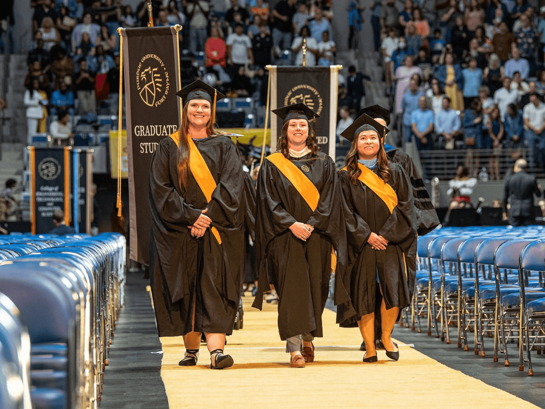 Three people marching down the aisle at a commencement