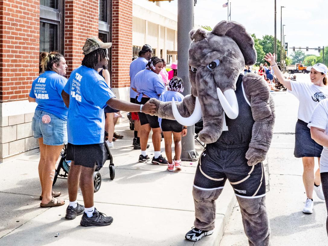 Don the mastodon is shaking hands with a parade-goer