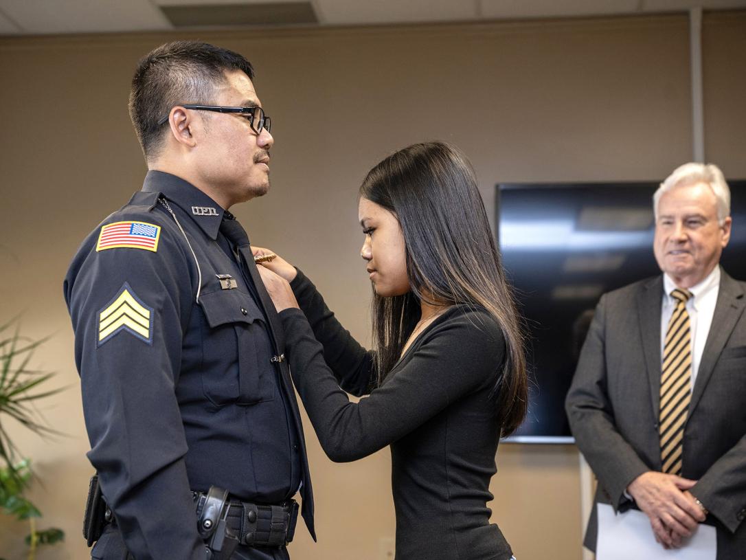 A police officer's badge is being pinned on by his wife.