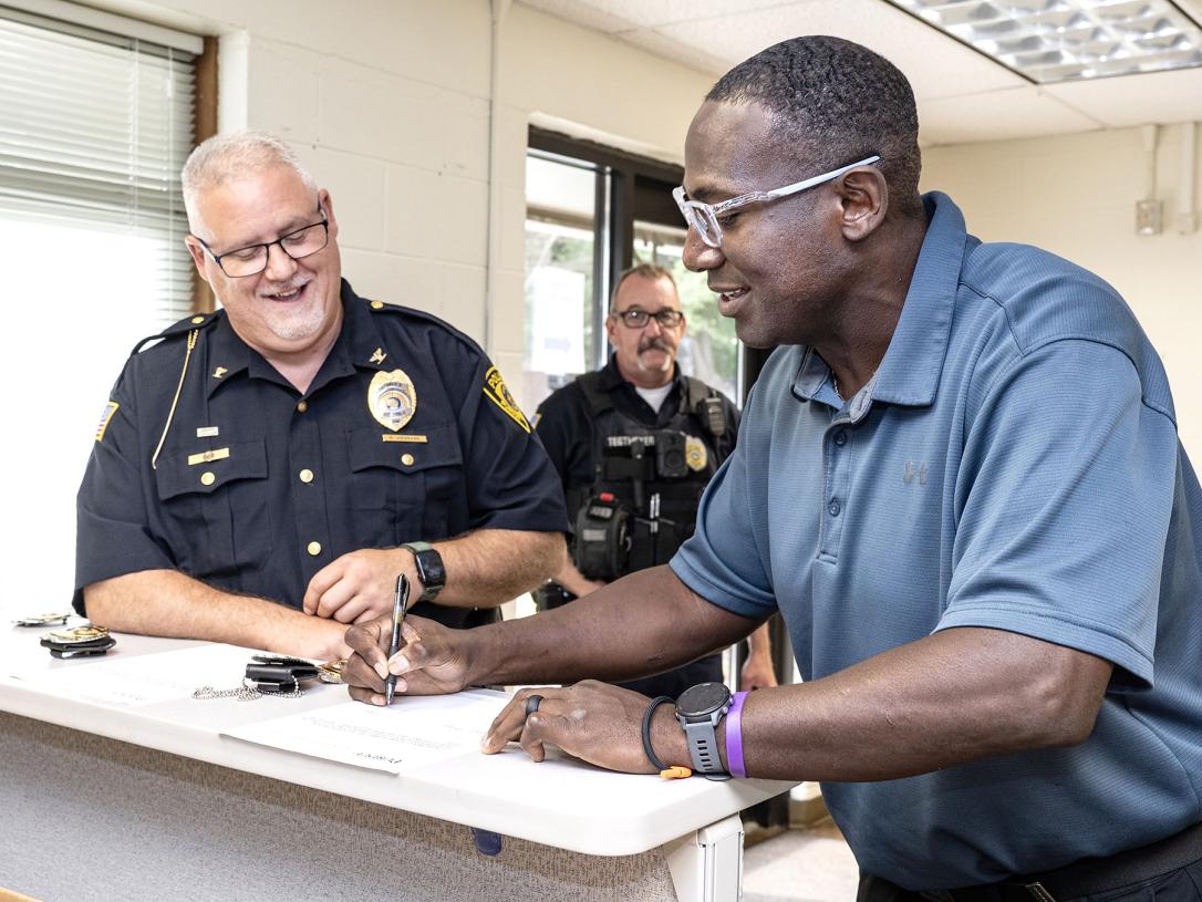 A newly sworn-in police officer is signing a document.