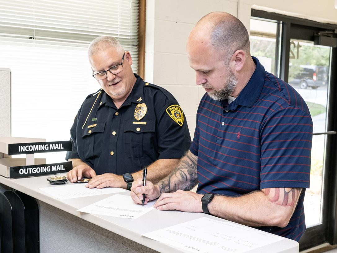 A newly sworn-in police officer is signing a document.