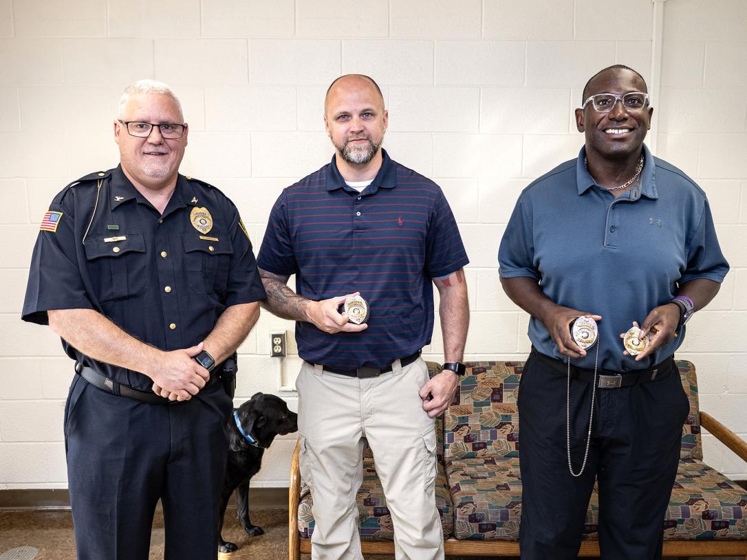 The chief of police is standing next to two newly sworn-in officers.