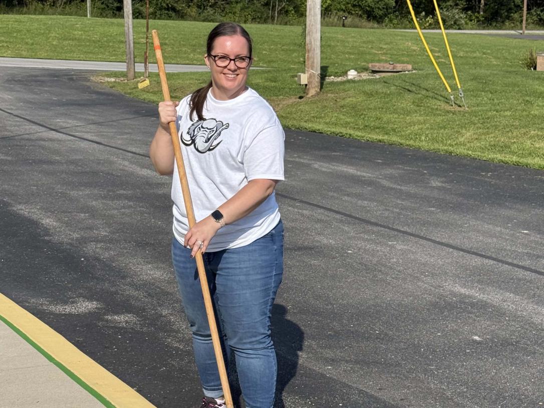 A volunteer is painting lines on a parking space