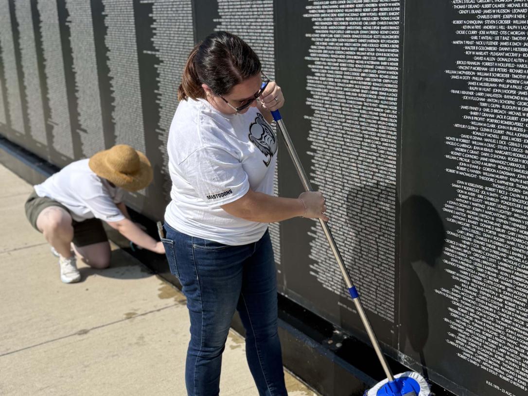 A volunteer is cleaning a veterans memorial wall