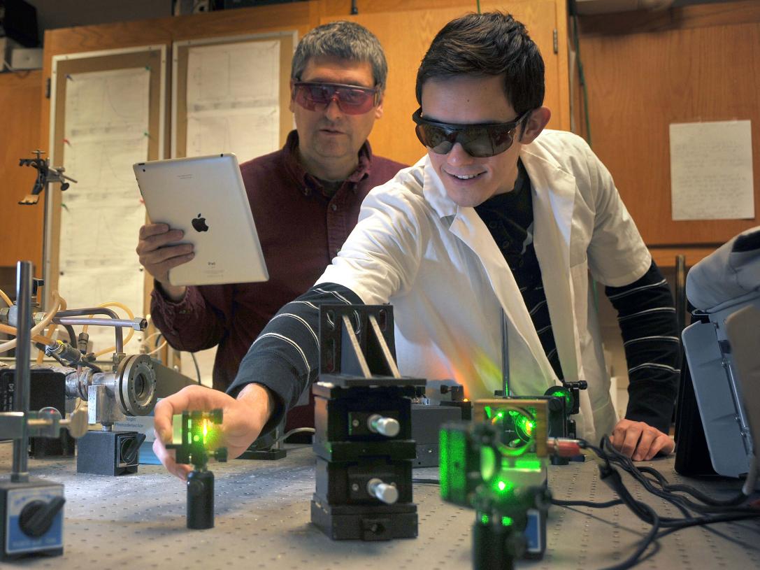 Physics professor and student working with lasers in a laboratory setting.