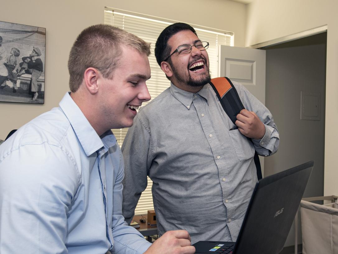 PFW students laughing over something they are viewing on their laptop computer.