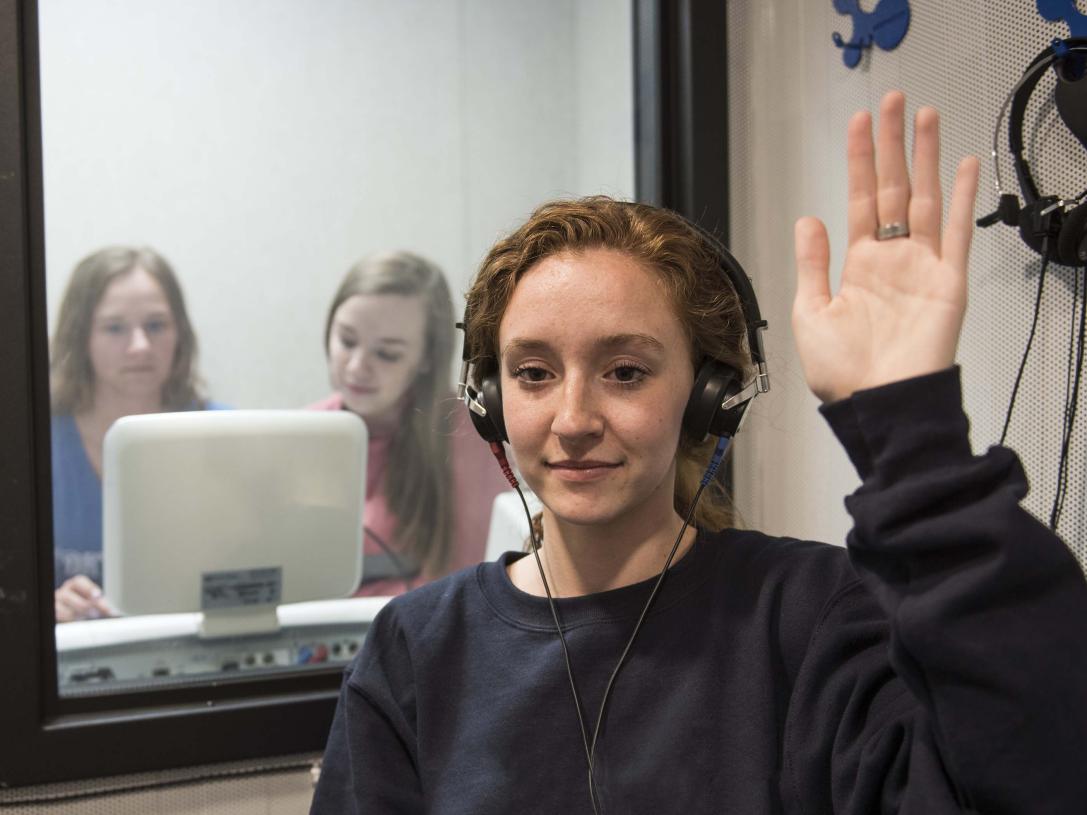 Communication science and disorders students testing a subject's hearing in a mock lab setting.