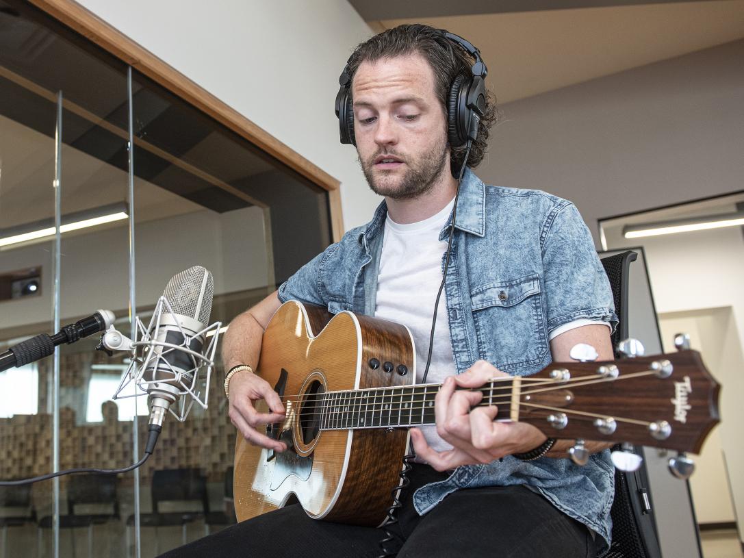 A student plays his guitar in a Sweetwater recording studio