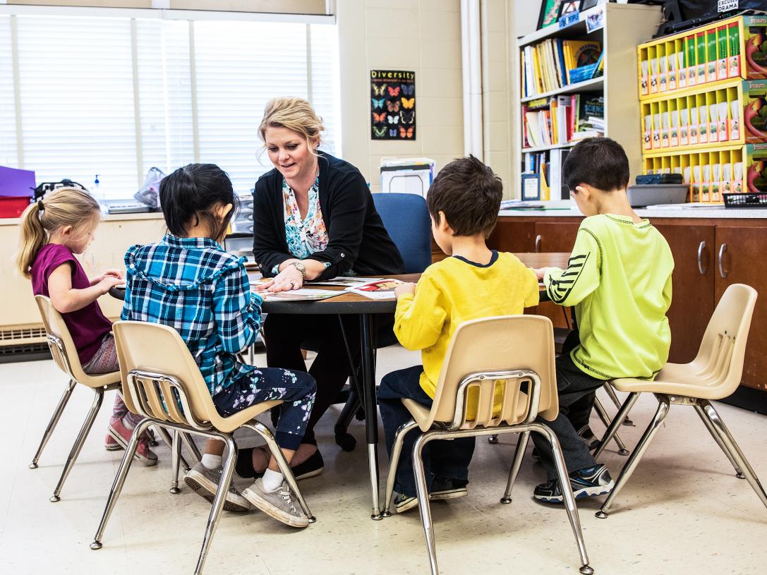 A female teacher at a table of elementary students