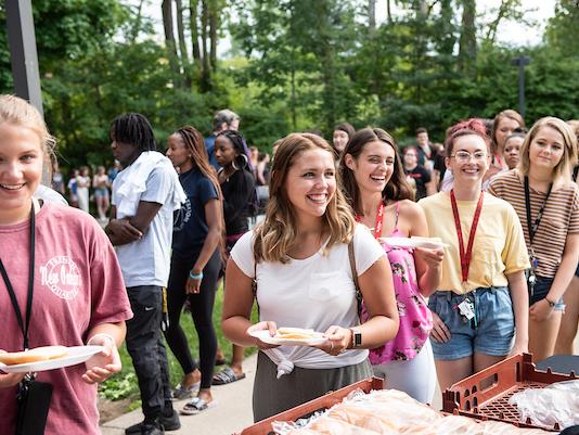Smiling students standing in line for a meal at campus kickoff