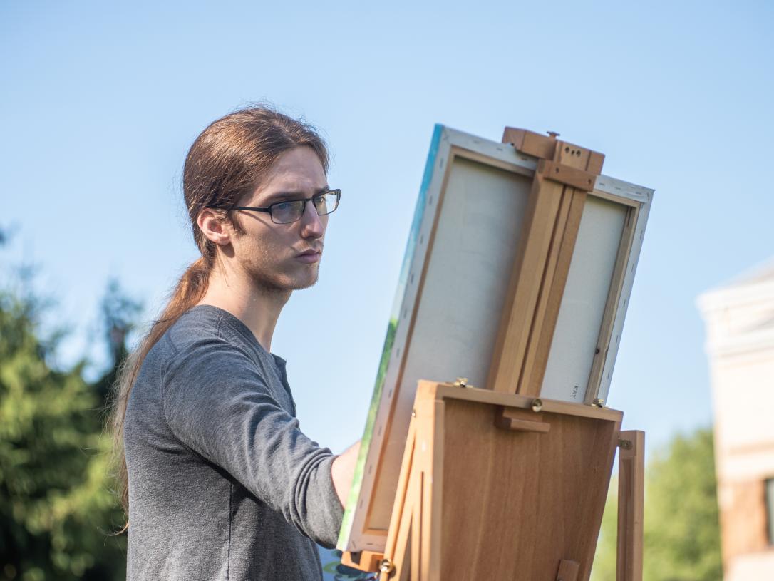 Student painting outdoors on campus.