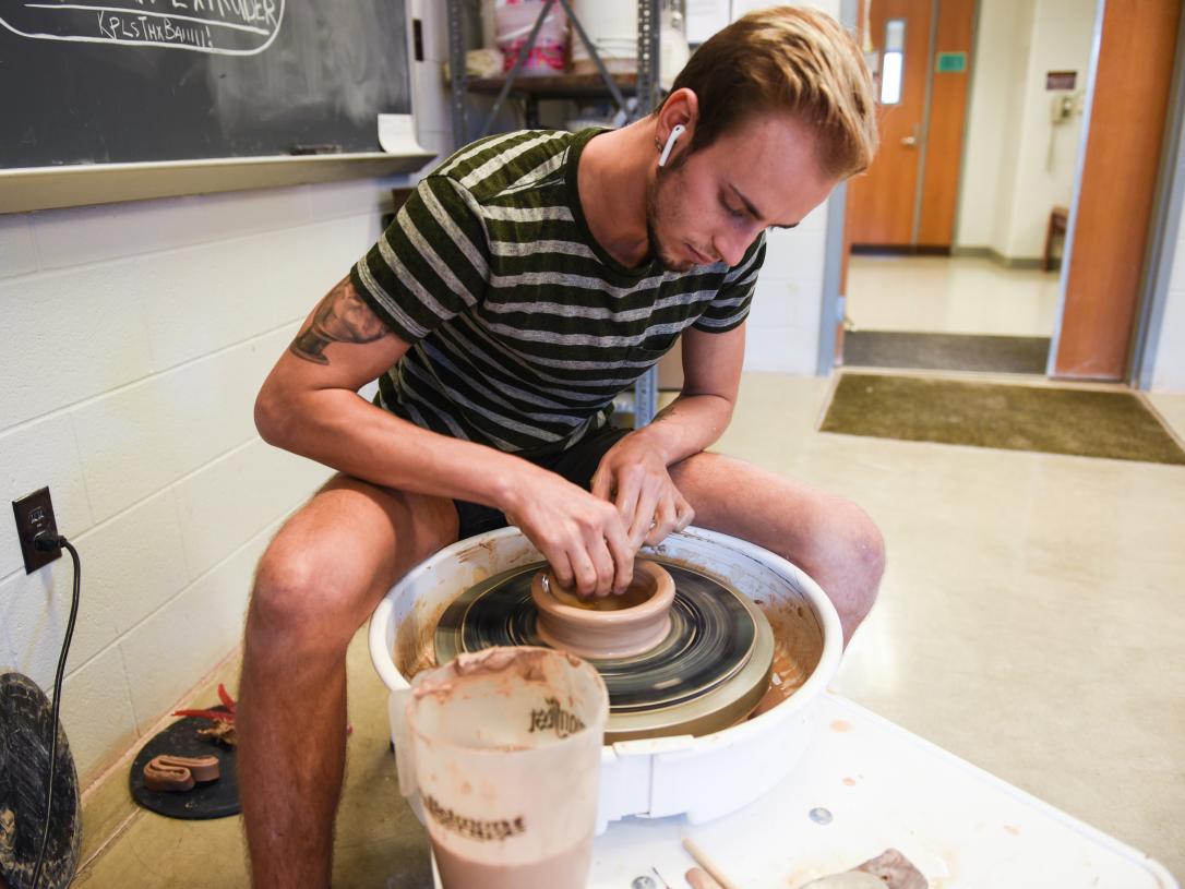 Student throwing on a pottery wheel.