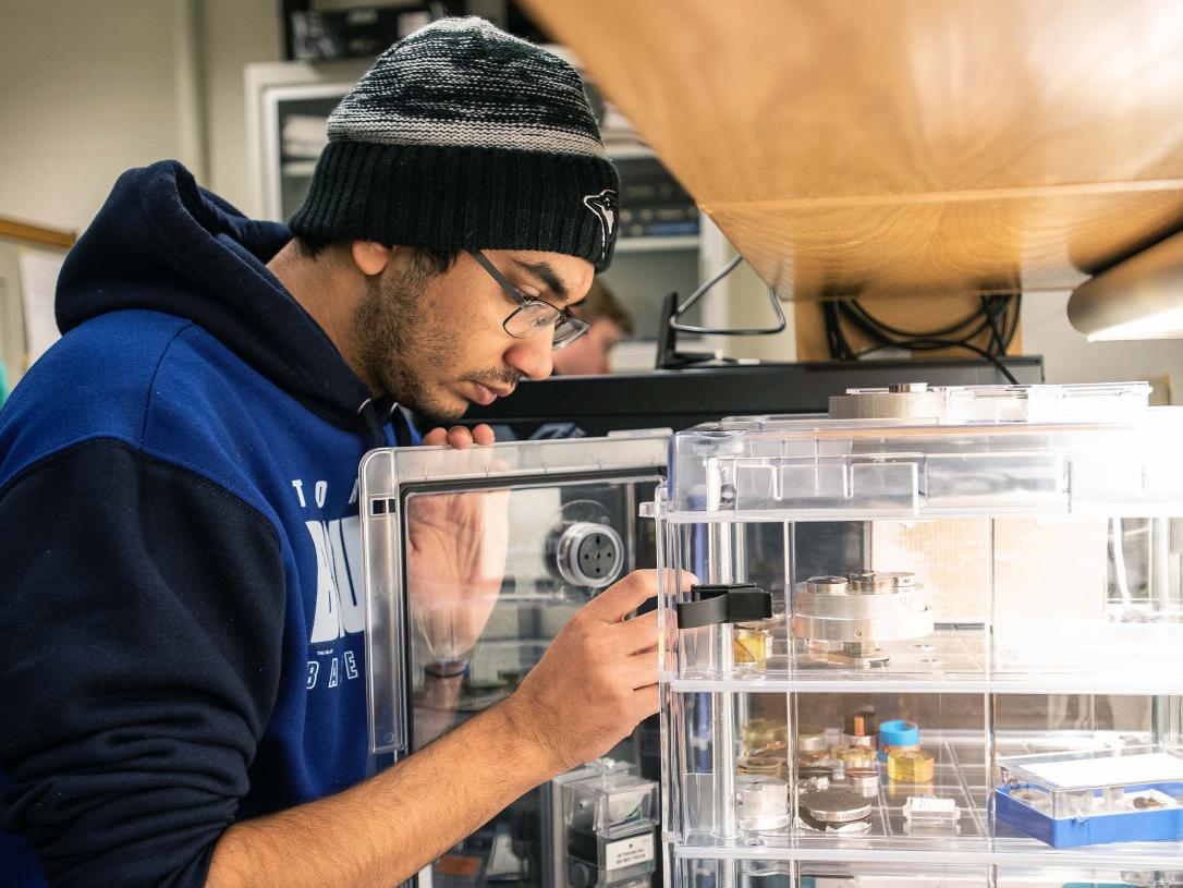 Physics student observing samples in a SEM lab.