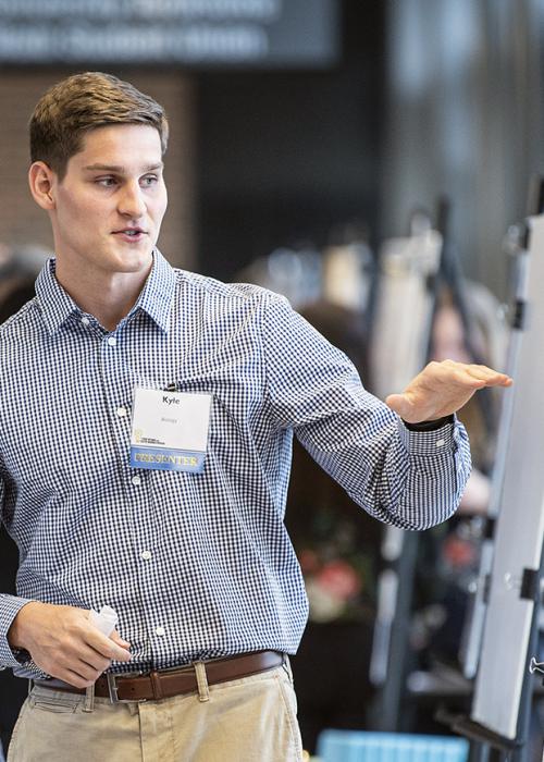 A student presents research at a symposium in the Sky Bridge.